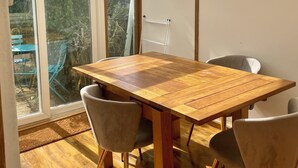 Un coin repas avec une table et des chaises en bois, de grandes fenêtres et une pancarte indiquant : « ON VEND DE LA LIMONADE ICI ».