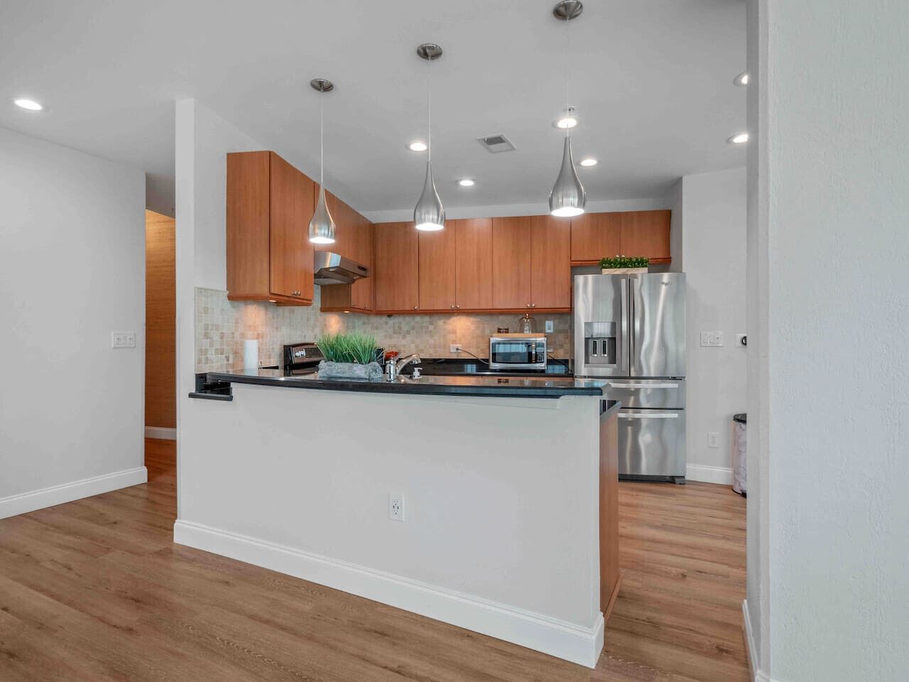 Una cocina moderna con armarios de madera, electrodomésticos de acero inoxidable e iluminación colgante.