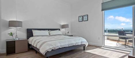 Une chambre à coucher avec un lit, des tables de chevet et une vue sur l’extérieur.