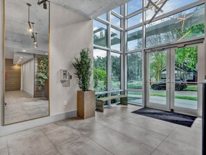 Un hall d’entrée moderne avec de grandes fenêtres, un banc en bois et une plante en pot.