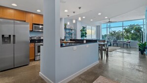 A modern kitchen with stainless steel appliances, a central island, and a dining area with a view. - Luxurious 2/2 Downtown Apartment (Orlando)