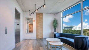 Een moderne wachtruimte met een houten vloer, een blauwe bank en twee ronde tafels.