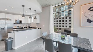 Een moderne keuken met roestvrijstalen apparatuur, hanglampen en een groot raam met uitzicht op een gebouw.