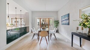 Comedor moderno con mesa de vidrio, sillas blancas y vista al exterior.