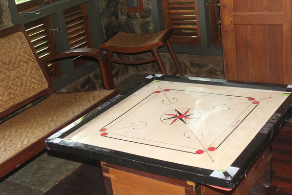 Una mesa de billar en una habitación con muebles de madera y paredes de piedra.