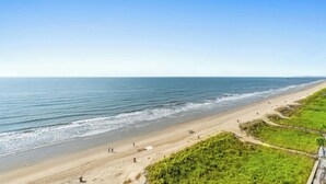 A beach with a clear sky, sandy shore, and some greenery. - Sunrise Pointe 9E-Oceanfront 3BR-Pool, Hot Tub (North Myrtle Beach)