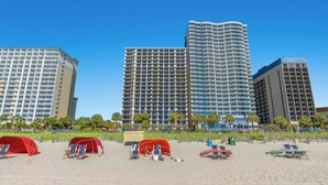 A beachfront hotel with multiple high-rise buildings, beach tents, and sun loungers. - Breakers 372-Oceanfront 1BR - Close to Boardwalk (Myrtle Beach)