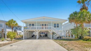 A two-story building with a covered entrance and a staircase leading to a second floor. - The Reagan- 4BR Channel House-Hot Tub (North Myrtle Beach)