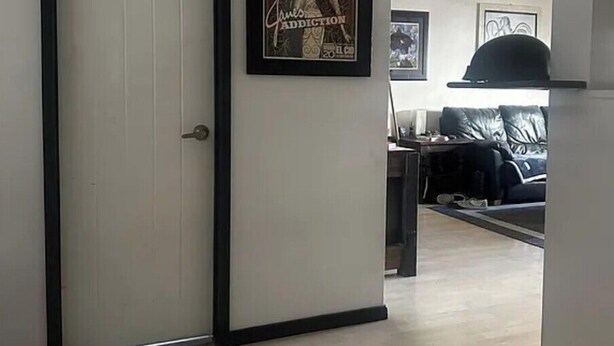 Een doorgang naar een woonkamer met een ingelijste poster aan de muur, een bank en een salontafel.