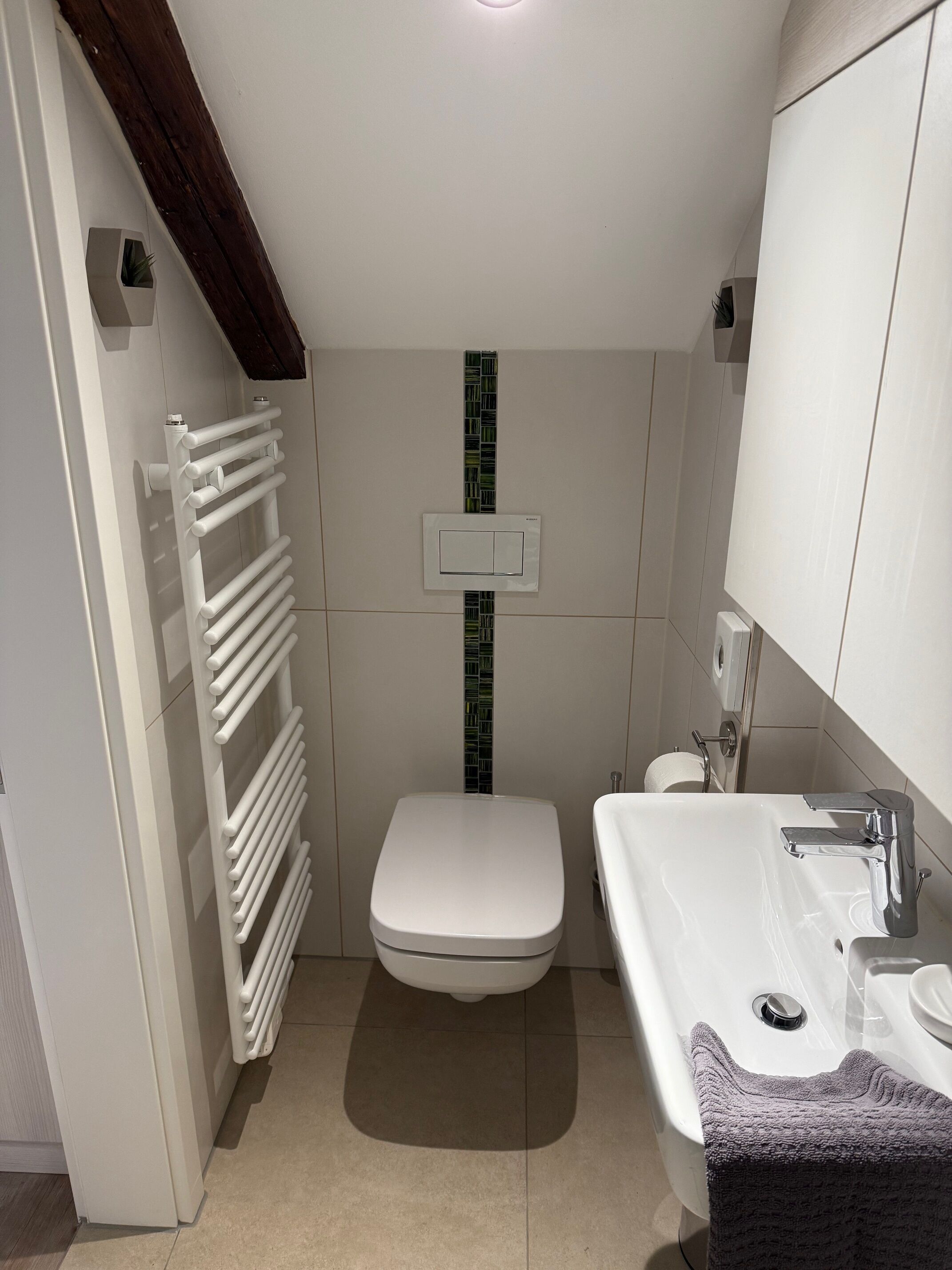A compact bathroom with a toilet, sink, and towel rack.