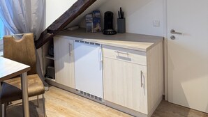 A compact kitchen with a built-in dishwasher, a coffee maker, and a potted plant on the ceiling. - Lucky Home Relax Apartment (Füssen)
