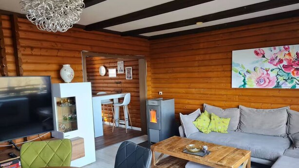 A modern living room with a wooden interior, a grey sofa, a wooden coffee table, and a television. - Near Pullmann City - small house in the middle of nature... Vacation for the whole year... (Windorf)