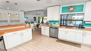 A modern kitchen with white cabinetry, a wooden countertop, and a large window. - Amazing - 4 Bed Billiard Table Luxury Canal Pool (Cape Coral)