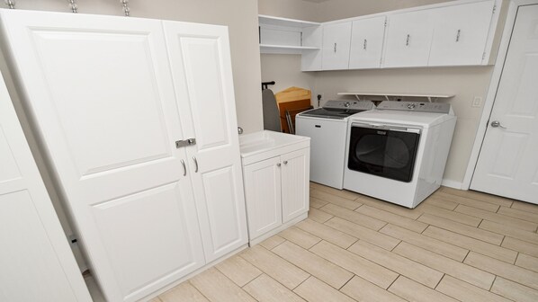 A laundry room with white cabinets, a washing machine, and a dryer. - Amazing - 4 Bed Billiard Table Luxury Canal Pool (Cape Coral)
