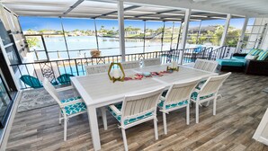 A covered patio with a table and chairs, overlooking a pool and a scenic view. - Amazing - 4 Bed Billiard Table Luxury Canal Pool (Cape Coral)