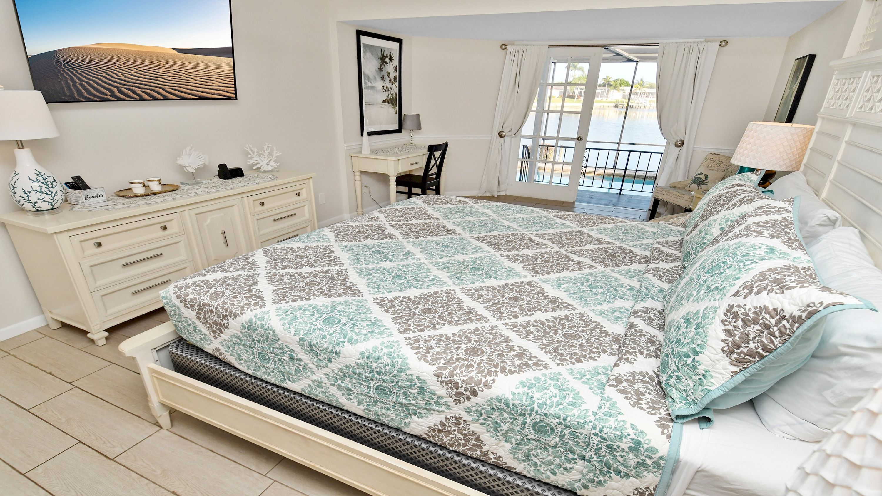 A bedroom with a bed, a desk, a chair, and a view of a pool.