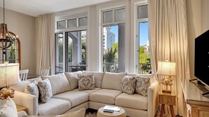 A modern living room with a sectional sofa, a round ottoman, and a TV.