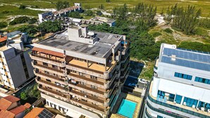 A multi-story hotel with a rooftop pool and ocean views. - Cf05 Prédio beira mar Apto 3 quartos (Cabo Frio)