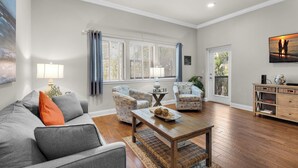 Una sala de estar con un sofá gris, dos sillones, una mesa de centro de madera y un mueble de madera.
