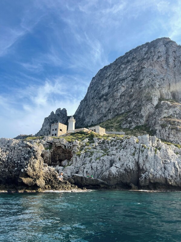 A coastal building with a rocky cliff backdrop, situated on a cliff overlooking the sea.