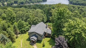 A house surrounded by dense forest with a view of a lake. - Chic Dog Friendly Chalet w/ Fire Pit & Hot Tub (McHenry)