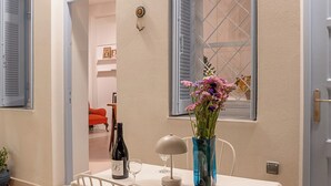 A dining area with a table set for two, a vase with flowers, and a bottle of wine. - Athenian Cypress House (Athina)