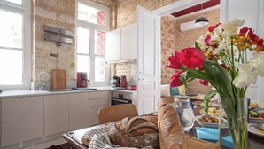 A kitchen with a brick wall, white cabinets, and a dining area with bread and flowers. - Athenian Cypress House (Athina)