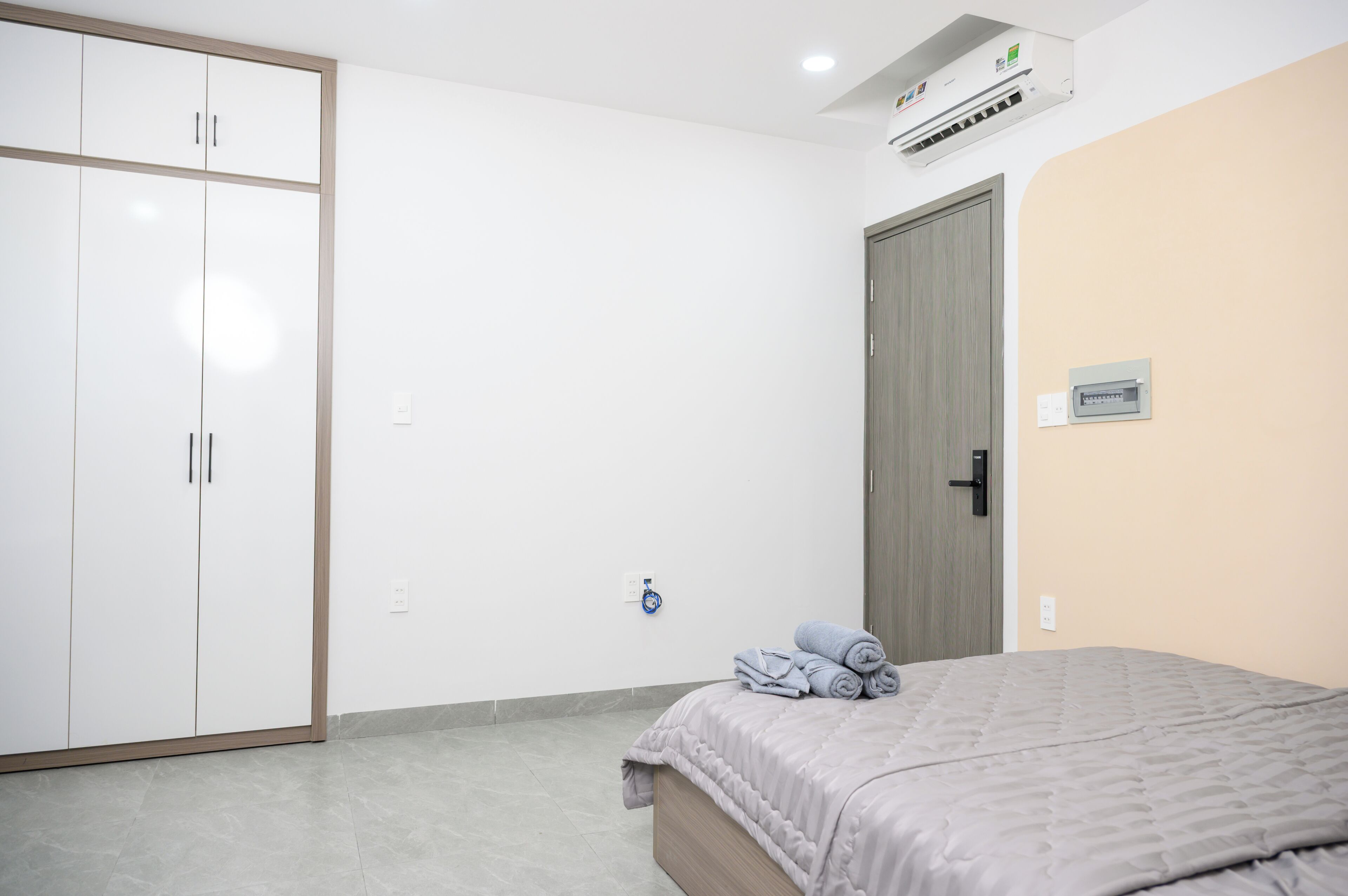 Une chambre à coucher comprenant un lit, une armoire, un appareil de climatisation et une porte.