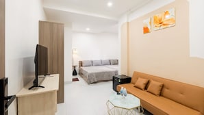 A hotel room with a bed, a sofa, a desk, a TV, and a small table. - Khai Linh Homestay (Ho Chi Minh City)