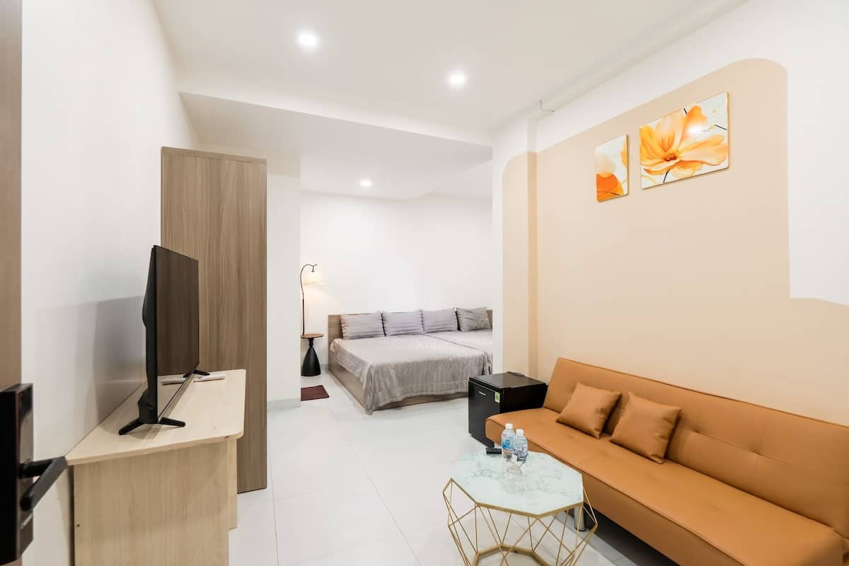 A hotel room with a bed, a sofa, a desk, a TV, and a small table.