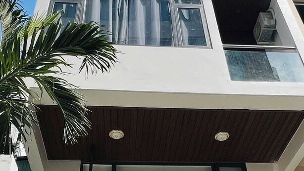 Een meerhoog gebouw met grote ramen, balkons en wat groen.