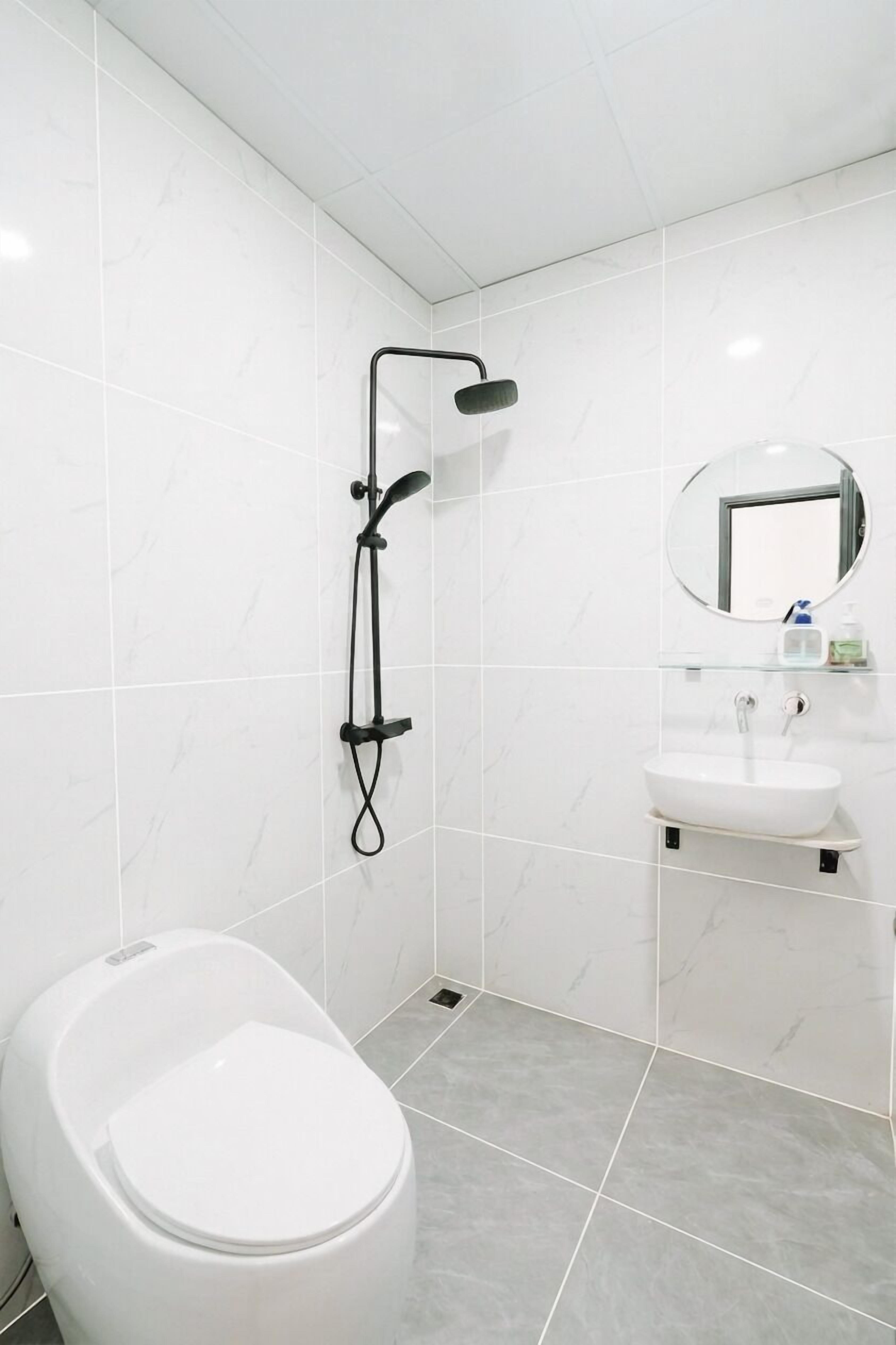 A bathroom with a toilet, a shower, a sink, and a mirror.