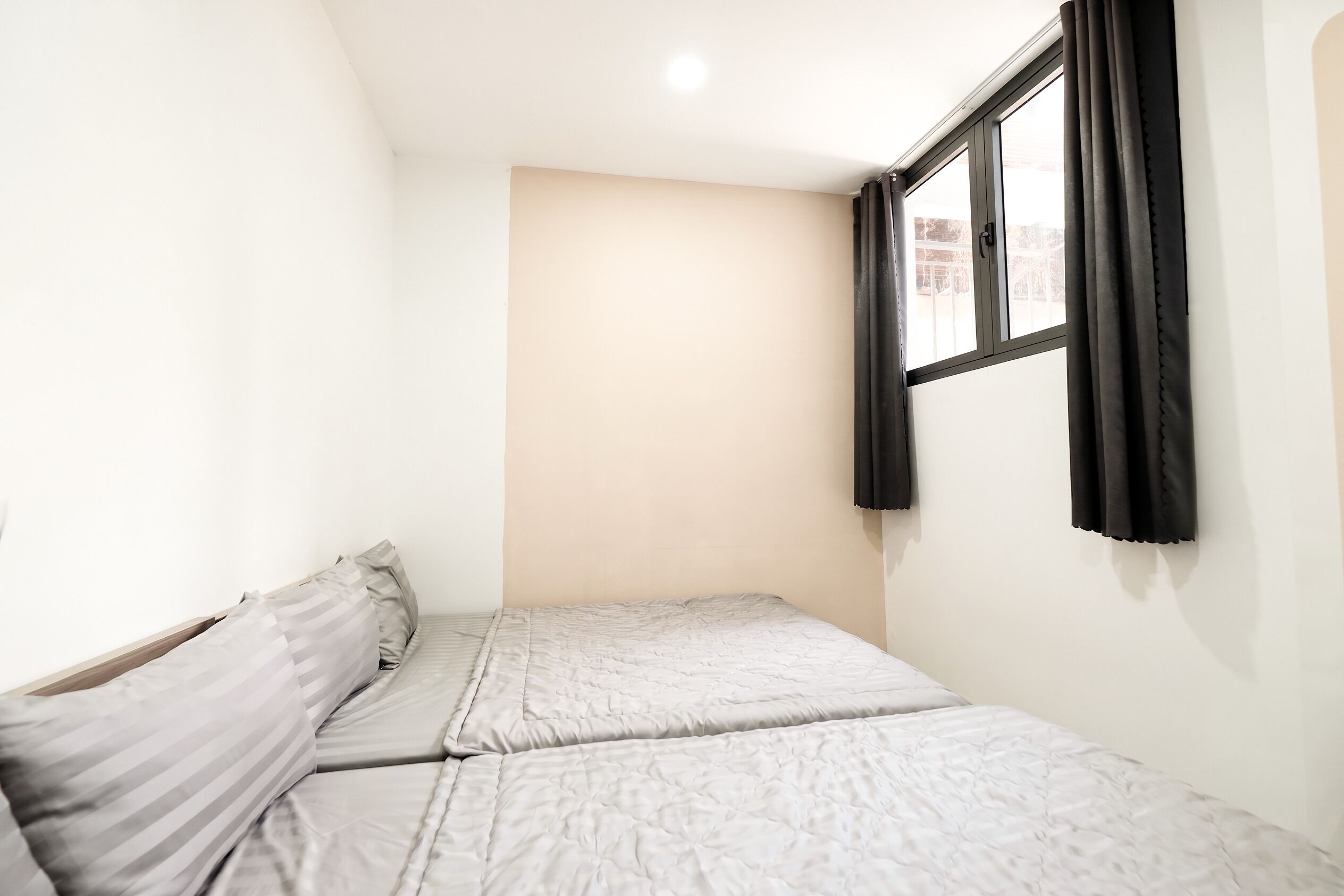 Une petite chambre avec un lit simple, une fenêtre, un mur de couleur claire et un plafond uni.