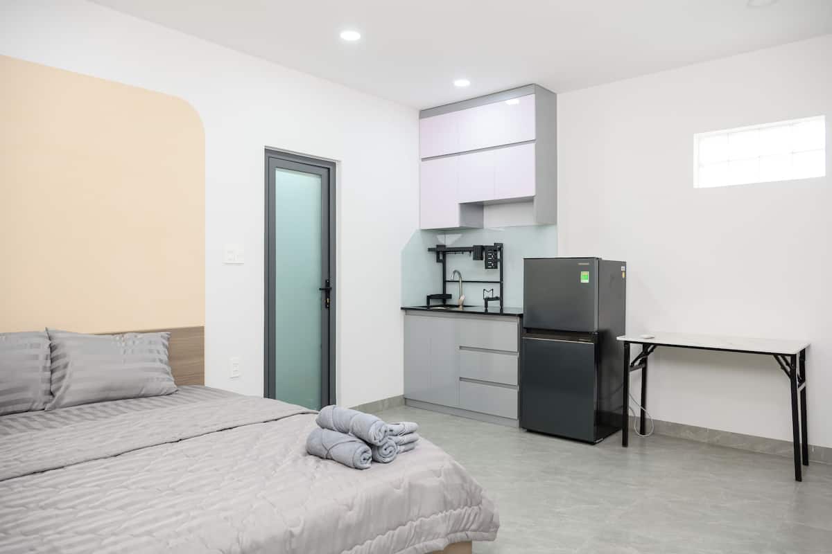 A compact room with a bed, a kitchenette, and a small table.