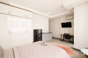 Une chambre d’hôtel moderne équipée d’un lit, d’une armoire, d’un bureau, d’une chaise et d’un téléviseur à écran plat.