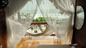 A hammock chair with a view of the ocean, a wooden floor, and a bed with a white headboard. - Casa Dos Almas (Santa Marta)