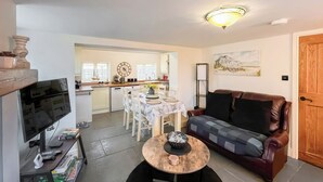 Ett vardagsrum med en TV, en soffa, ett soffbord och en matplats med ett bord och stolar.