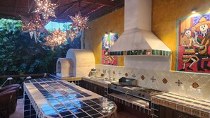 A kitchen with a tiled backsplash, a stove, and hanging lights.