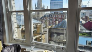 A room with two chairs, a table, and a view of a cityscape through large windows. - City centre location studio (Bristol)