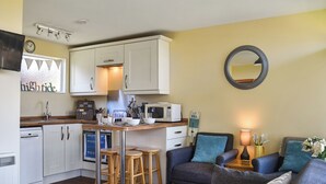 A compact living space with a kitchenette, a sofa, a coffee table, and a mirror.