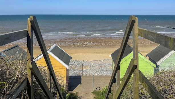 A wooden staircase leading to beach huts with a view of the sea.
