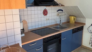 A compact kitchen with blue cabinets, a black dishwasher, and a tiled backsplash. - Beautiful top floor apartment with balcony in Osloß (Osloß)