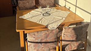 A dining area with a wooden table, patterned chairs, a chandelier, a bookshelf, and a framed picture on the wall. - Beautiful top floor apartment with balcony in Osloß (Osloß)