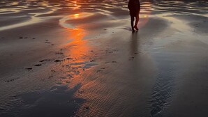 A beach scene with a person walking towards the sunset. - NEW! Walk to town and beach, Balcony, Romantic, (Sandpiper Approach) (Long Beach)