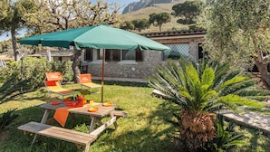 Un patio con tavolo, sedie e un ombrellone verde.