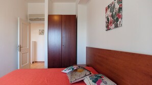 Una camera da letto con copripiumino rosso, testiera in legno e decorazioni murali floreali.