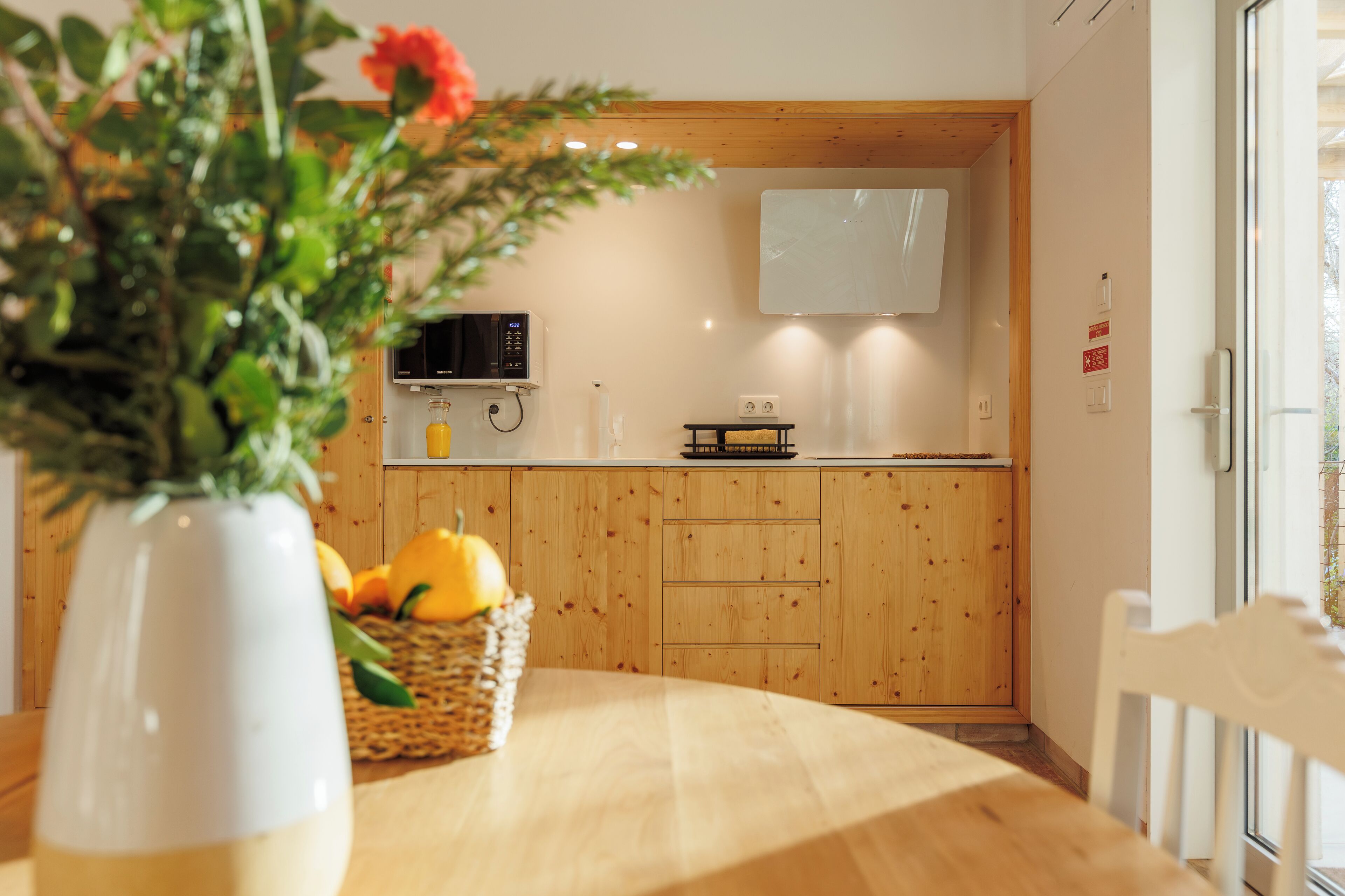 A kitchen with wooden cabinets, a microwave, and a basket of fruit on the counter.