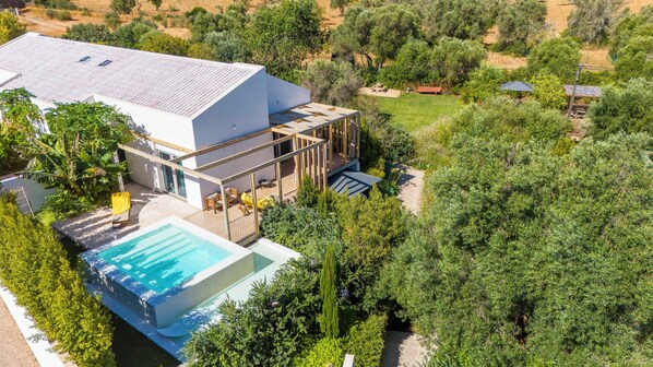 A modern house with a large swimming pool, a covered patio, and a lush garden. - Laranjal Farm House (Olhao)
