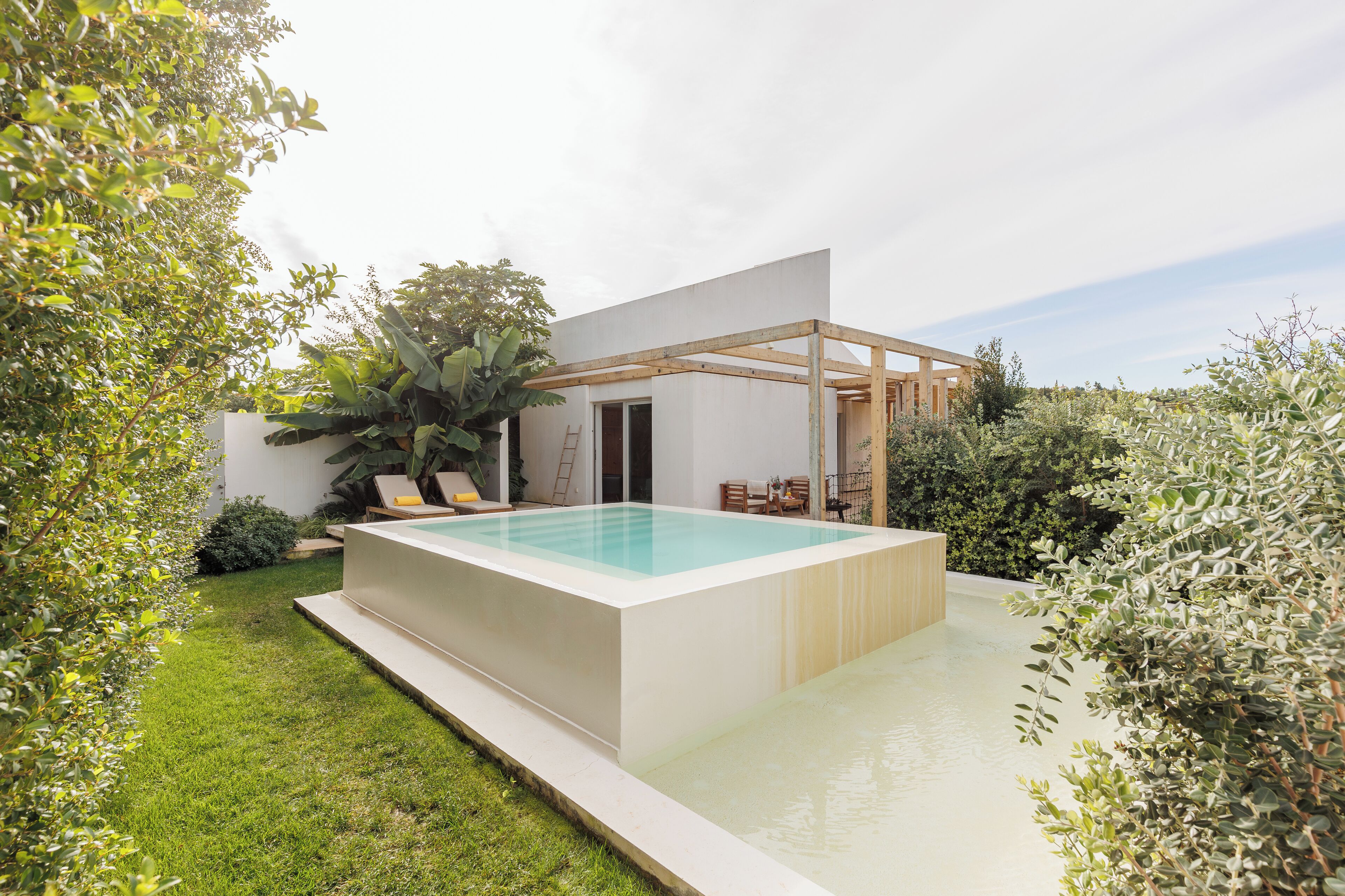 A modern house with a rectangular swimming pool, a wooden pergola, and a well-maintained garden.