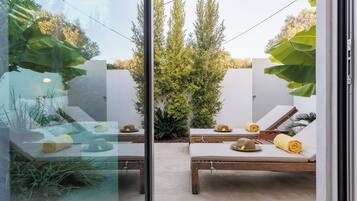 Un área de descanso al aire libre y de diseño moderno con dos sillones de madera, cada uno con una toalla y un sombrero.